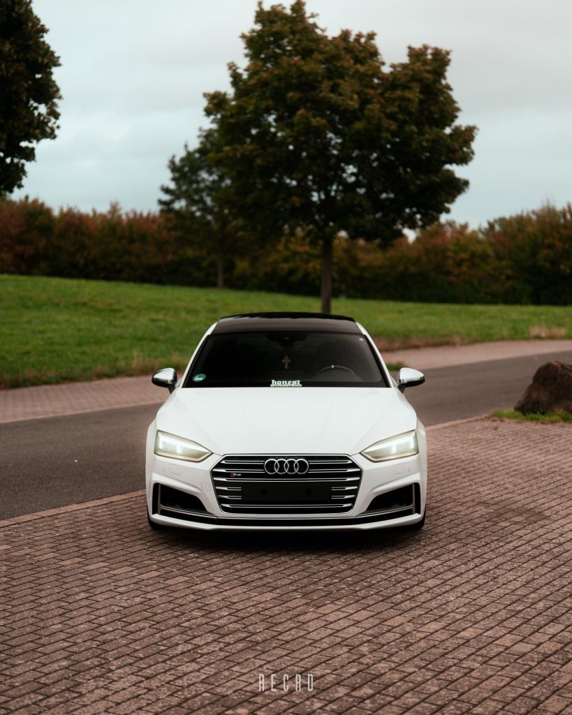 Weißer Audi S5 frontal mit eingeschalteten Scheinwerfern